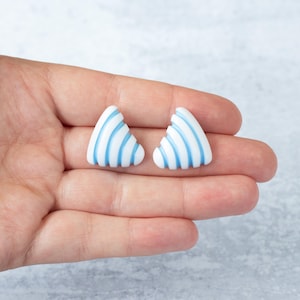May include: A pair of white triangle shaped earrings with blue stripes.