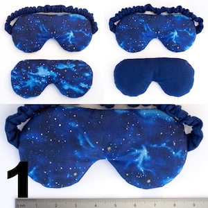 May include: A blue sleep mask with a galaxy print and gold stars. The mask has an elastic band for a comfortable fit. The mask is shown in three different positions.