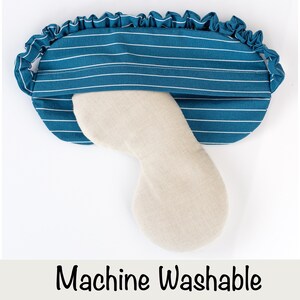 Puede incluir: Una m&aacute;scara para dormir de color turquesa con rayas blancas y borde con volantes. La m&aacute;scara tiene un inserto beige curvado y el texto "Machine Washable" en la parte inferior. Esta m&aacute;scara est&aacute; dise&ntilde;ada para la comodidad y el bloqueo de la luz.