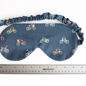 以下が含まれることがあります： 小さなカラフルな自転車が繰り返し描かれた、濃い青色のアイマスク。快適なフィット感を実現する伸縮性のあるバンドが付いています。