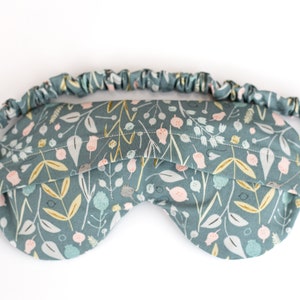 May include: A blue sleep mask with a floral pattern. The mask has an elastic band for a comfortable fit.