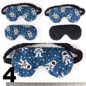 May include: A blue sleep mask with a white astronaut and star pattern. The mask has a black elastic band. The number 4 is visible in the bottom left corner of the image.