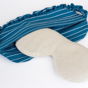 Puede incluir: Una m&aacute;scara para dormir a rayas azul verdoso y blancas con una cubierta para los ojos beige. La m&aacute;scara tiene una banda el&aacute;stica con volantes. La cubierta para los ojos es de color beige claro y est&aacute; dise&ntilde;ada para adaptarse alrededor de los ojos. La m&aacute;scara para dormir est&aacute; dise&ntilde;ada para bloquear la luz.