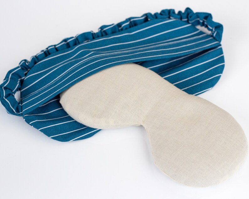 Puede incluir: Una m&aacute;scara para dormir a rayas azul verdoso y blancas con una cubierta para los ojos beige. La m&aacute;scara tiene una banda el&aacute;stica con volantes. La cubierta para los ojos es de color beige claro y est&aacute; dise&ntilde;ada para adaptarse alrededor de los ojos. La m&aacute;scara para dormir est&aacute; dise&ntilde;ada para bloquear la luz.