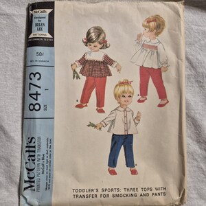 May include: Vintage McCall's pattern 8473 for toddler's sports clothing. The pattern features illustrations of three tops with pants, designed for smocking and transfer. The cover shows drawings of children wearing the outfits.