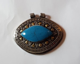 May include: A silver pendant with a blue turquoise stone set in a silver and gold ornate frame.