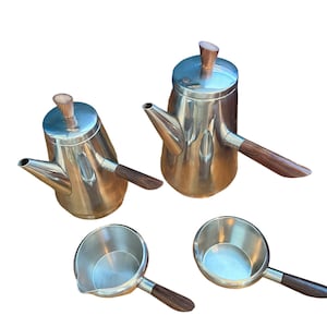 May include: A set of four stainless steel coffee pots with wooden handles. The pots are different sizes and have a polished finish.