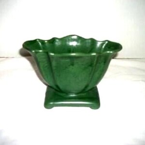 May include: A green ceramic bowl with a scalloped rim and a square base. The bowl has a glossy finish and a fluted design. The bowl is a dark shade of green and is likely vintage.