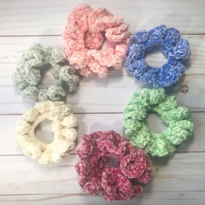 May include: Six colorful scrunchies made of soft, fuzzy fabric. The scrunchies are in shades of pink, blue, green, white, and red.