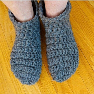 May include: A pair of gray crocheted slippers. The slippers are made with a simple stitch and have a soft, cozy look.