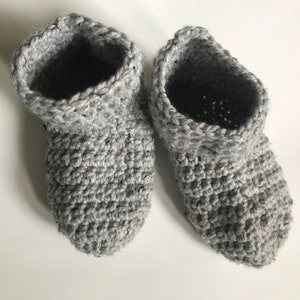 May include: A pair of gray crocheted slippers with a textured pattern.