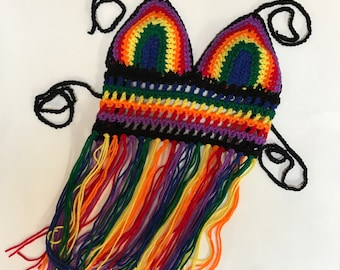 May include: A rainbow crochet top with black straps and a fringe trim. The top is made with a variety of colors, including red, orange, yellow, green, blue, and purple.