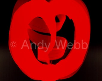 May include: A vibrant red light painting against a solid black background, featuring a circular, abstract shape with layered, glowing strokes. The text Andy Webb is visible in white across the center of the composition, overlaid on the red light.