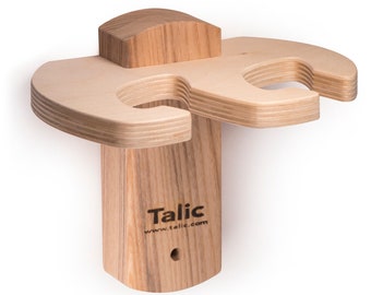 May include: Wooden wall mount with two cup holders, made of light wood with a natural finish. The mount has a small hole for hanging and the text "Talic www.talic.com" is engraved on the front.