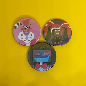 May include: Three round pinback buttons with cartoon character designs. One button features a character in a top hat with heart-shaped glasses, another shows a woman with red hair, and the third has a blue screen character with a bow tie.