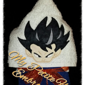 May include: White hooded towel with an embroidered cartoon character with black hair and a serious expression. The towel has a red ribbon tied around it and the text "My Petite Fleur Embroidery" is visible on the towel.