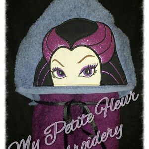 Puede incluir: Toalla con capucha morada con una imagen bordada de una mujer con cabello morado y ojos grandes. La toalla tiene un lazo de cinta negro y el texto "My Petite Fleur Embroidery" está bordado en la parte inferior.