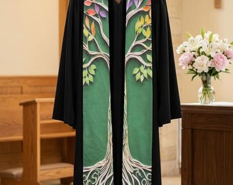 Puede incluir: Una sotana negra con una estola verde con un diseño de árbol. El árbol tiene hojas coloridas y raíces blancas. La túnica se exhibe en un soporte de madera en un entorno eclesiástico.