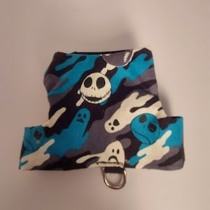 Puede incluir: Un arnés para mascotas con un patrón azul, gris y blanco con diseños de fantasmas de dibujos animados y Jack Skellington. El arnés tiene un anillo en D para la fijación de la correa.