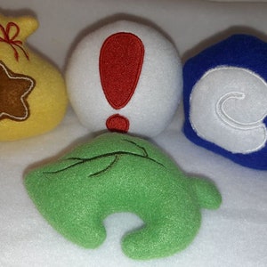 May include: A collection of plush toys featuring designs from the Animal Crossing video game. Includes a yellow bell bag with a brown star, a white exclamation point, a blue shell, and a green leaf.