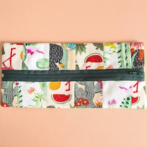 May include: A zippered pencil case with a patchwork design featuring various fruits, cacti, and geometric patterns in shades of green, pink, red, and black.