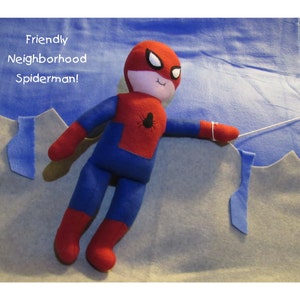 May include: A red and blue plush toy Spiderman with a white face and black eyes. The toy is hanging from a string and has the text "Friendly Neighborhood Spiderman!" written above it.