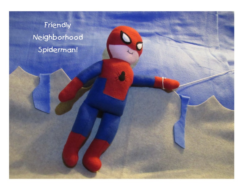 May include: A red and blue plush toy Spiderman with a white face and black eyes. The toy is hanging from a string and has the text "Friendly Neighborhood Spiderman!" written above it.