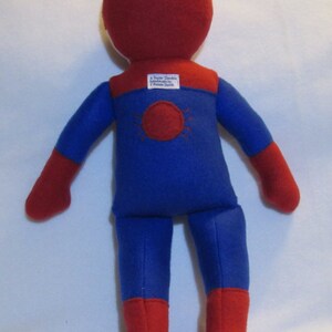 May include: A red and blue felt superhero doll with a spider symbol on the back. The doll is handmade by "Super Darlin" and has a tag that says "Handmade by T. Renee Smith".