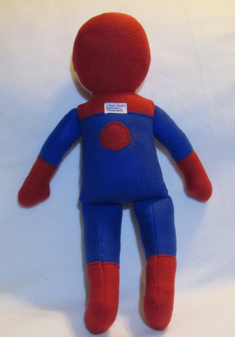 May include: A red and blue felt superhero doll with a spider symbol on the back. The doll is handmade by "Super Darlin" and has a tag that says "Handmade by T. Renee Smith".