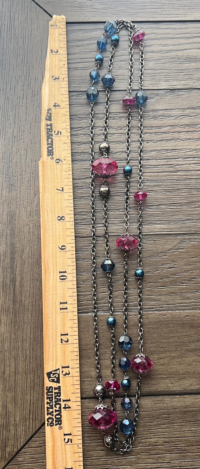 May include: A silver chain necklace with pink and blue faceted glass beads. The necklace is approximately 15 inches long.