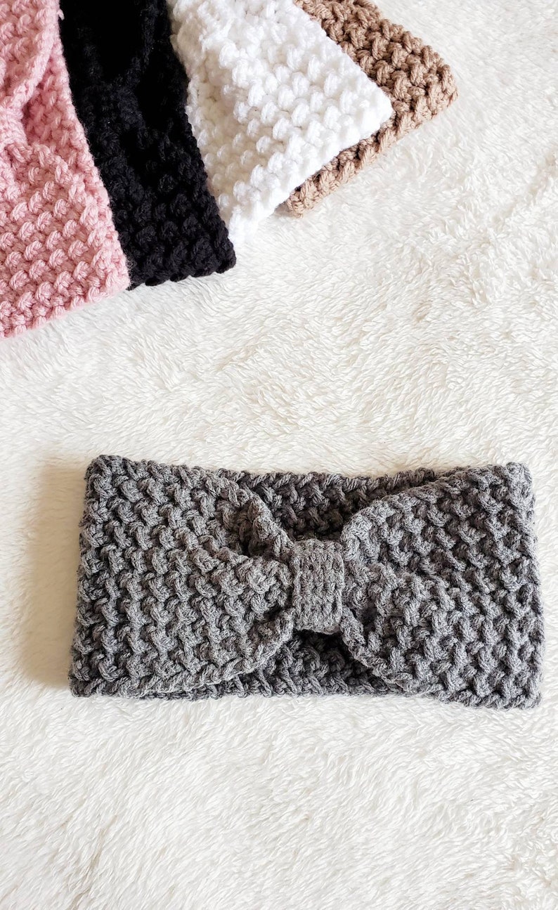 May include: A gray knitted headband with a bow detail. The headband is made of a soft, textured yarn.