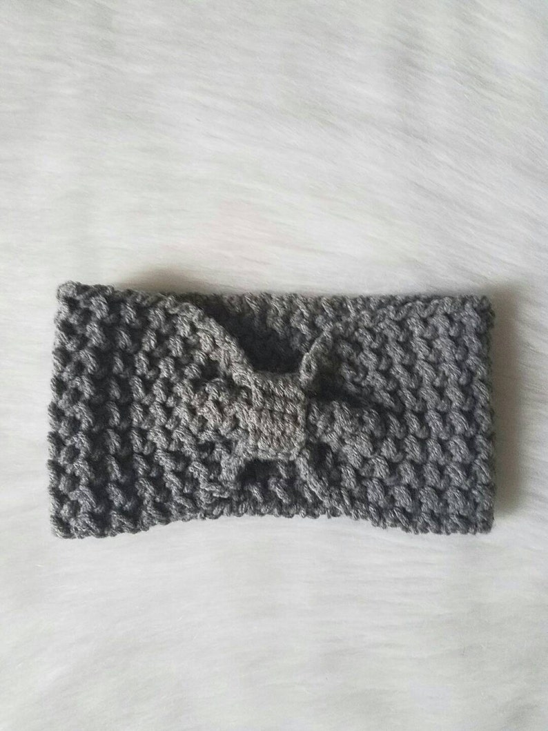 May include: A gray crocheted headband with a bow in the center.