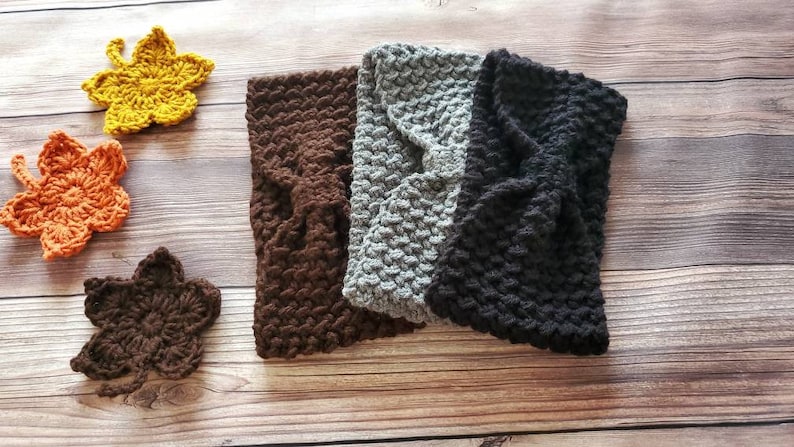 May include: Three crocheted headbands in brown, gray, and black. The headbands are made with a textured stitch and have a bow detail.
