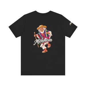 May include: A black short-sleeve t-shirt featuring a graphic of an elderly person wearing a straw hat, a colorful striped poncho, and sandals while holding a wooden staff. The text Michoacán is printed in white script below the figure.