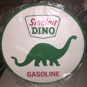 May include: A white round metal sign with a green dinosaur silhouette and the text "Sinclair DINO GASOLINE". The dinosaur is green and the text is red.