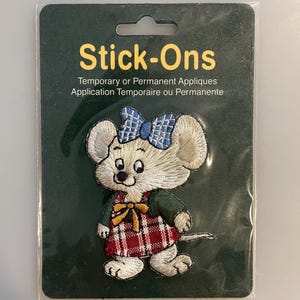 Peut inclure: Écusson de souris brodée avec un nœud bleu, un haut vert et une robe à carreaux rouges. L'emballage indique "Stick-Ons" et "Appliques temporaires ou permanentes".