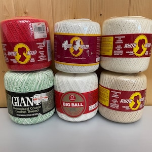 May include: Six spools of crochet thread in a variety of colours. The spools are labelled with the brands "South Maid", "Giant", and "Big Ball". The colours include red, white, green, and beige. Each spool is wrapped in plastic.