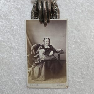喪服を着てボンネットをかぶった老婦人と小さな白い犬を描いたアンティーク CDV 写真。