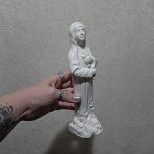 Vintage delicate and beautiful nun blessed Mary Angela figurine holding crucifix. Glazed white ceramic.