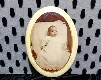 Antique Celluloid and tin memorial photo of a little baby dressed in white. Early 1900s.