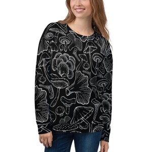 May include: Black sweatshirt with a white mushroom pattern. The long-sleeved top features a repeating design of various mushroom illustrations. The design is a detailed, botanical-style drawing of different types of fungi.