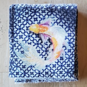May include: A stack of blue and white fabric squares with a white and orange fish design. The fabric has a geometric pattern.