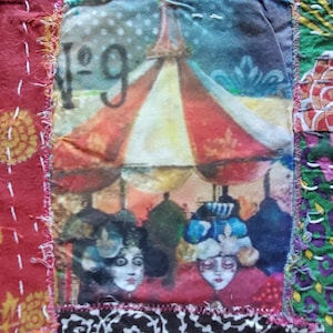 May include: A patchwork textile with a central image of a vintage scene with figures under umbrellas. The image is framed by colorful, stitched fabric squares in red, yellow, blue, and green. The number "1-9" is visible.