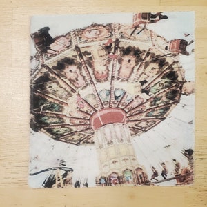 May include: A vintage-style carousel with colorful horses and intricate details. The carousel is painted in shades of pink, yellow, and brown. The carousel is suspended from the ceiling and is surrounded by a white background.