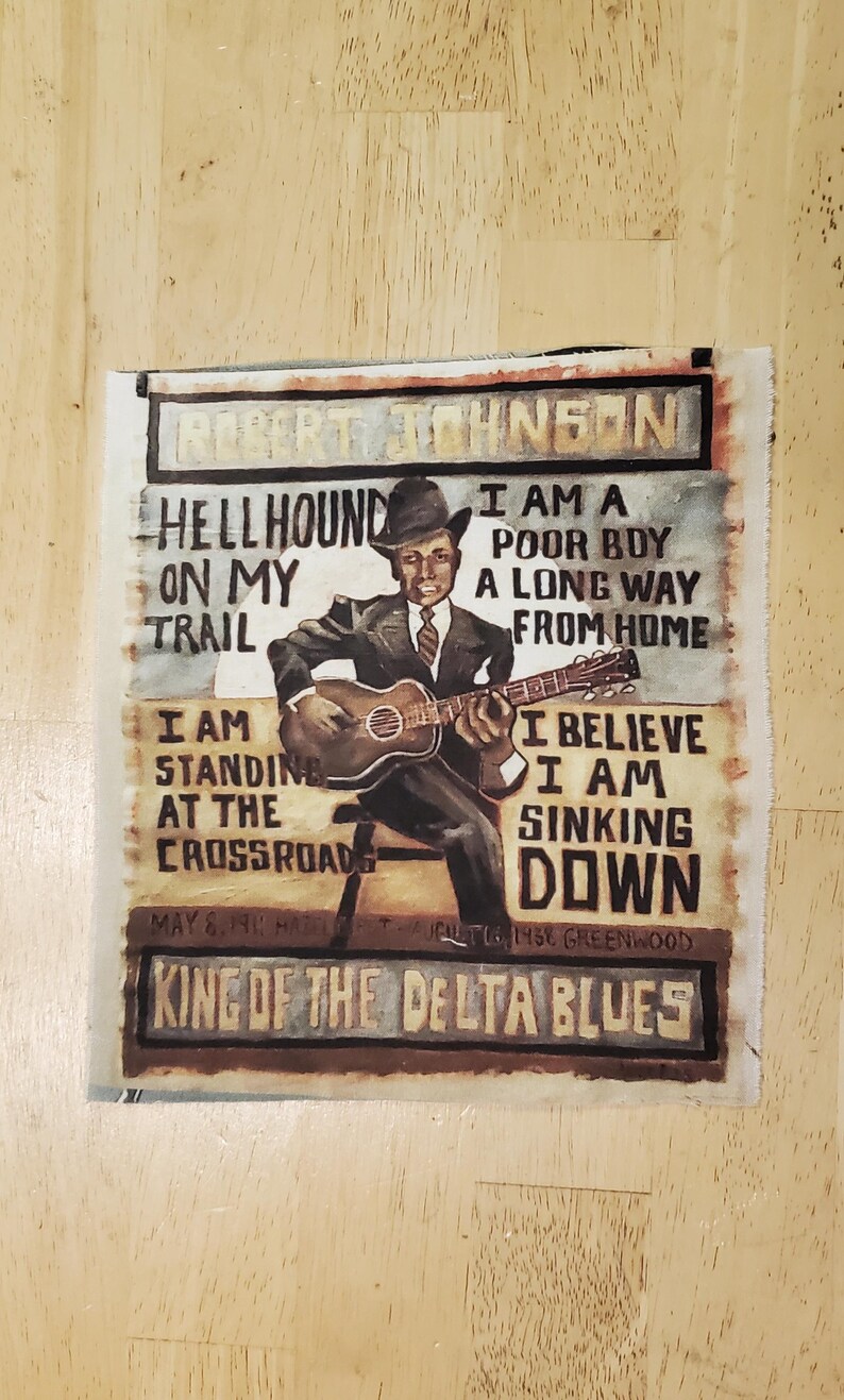 Pu&ograve; includere: Un'opera d'arte dipinta raffigurante Robert Johnson che suona la chitarra, con testo come "Hellhound on my trail" e "King of the Delta Blues". L'opera utilizza tonalit&agrave; marroni, nere e beige.