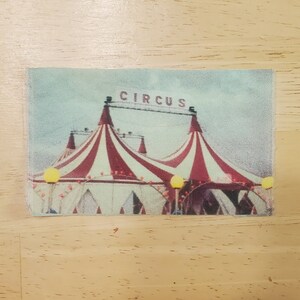 May include: A vintage-style image of a red and white striped circus tent with the word "CIRCUS" above it.