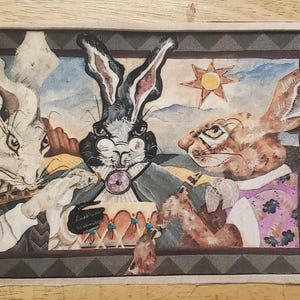 May include: A framed illustration of three rabbits with different colored fur. The rabbit on the left is white with black markings, the rabbit in the middle is black with white markings, and the rabbit on the right is brown with white markings. The rabbits are all wearing clothing and have human-like features. The background is a patterned design with a sun in the upper right corner.