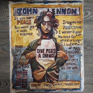 May include: A rectangular canvas painting of John Lennon with a yellow and blue background. The portrait features text including "Give Peace A Change" on a shirt, "John Lennon," and lyrics from "Imagine." The style uses bold, dark outlines.