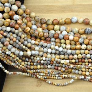 May include: A collection of round, multi-coloured agate beads with brown, white and orange patterns. The beads are strung on a string and are arranged in a fan shape.