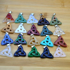 May include: Twenty-four assorted colour gemstone pendants with a Celtic knot design. Each pendant is carved from a different type of stone, including red, blue, green, brown, and white.